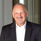 man with goatee facial hair wearing a white collar shirt and a black blazer