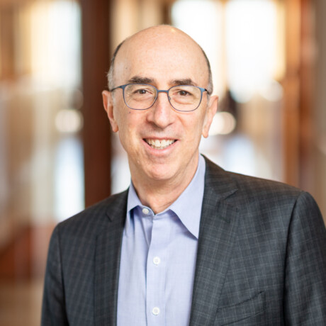 man with glasses wearing a blue collar shirt and gray blazer